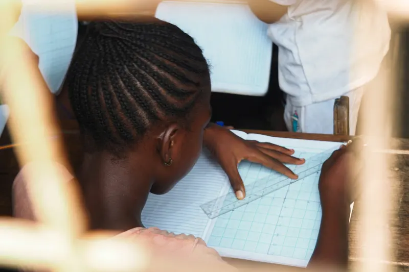 A student draws lines with a ruler in an exercise book
